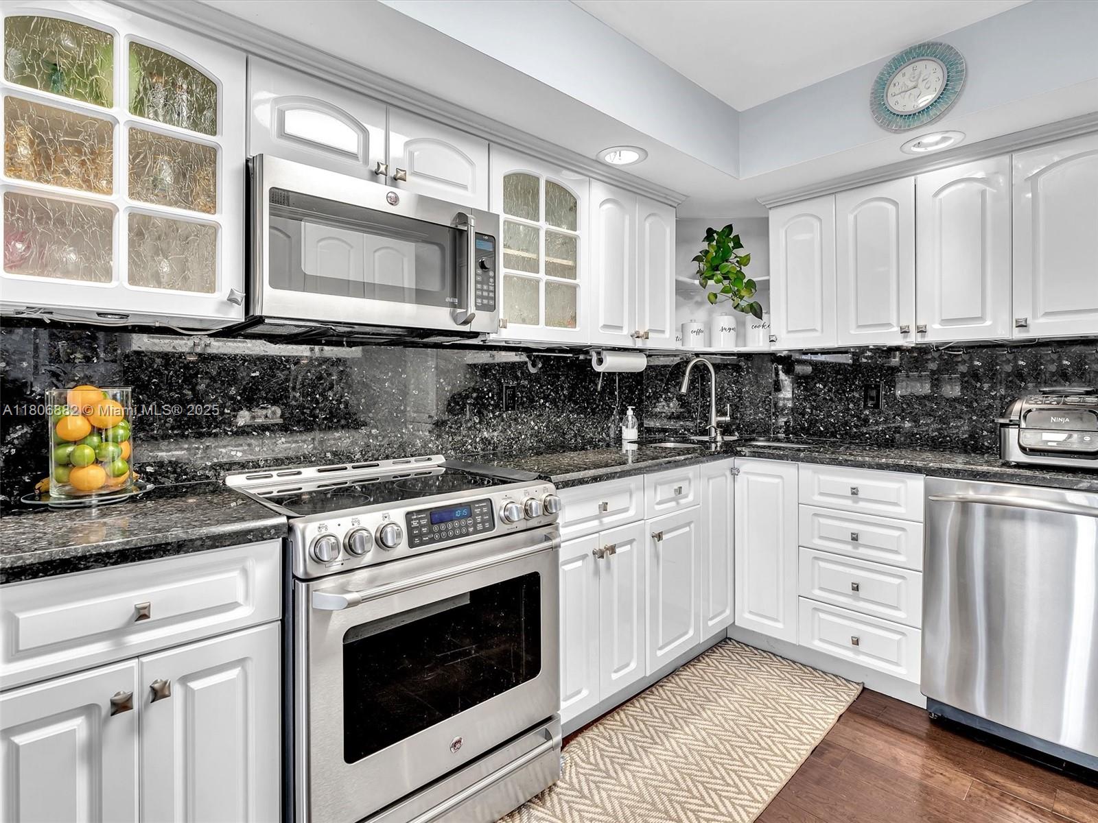 6423 Collins Avenue, Unit 409 Miami Beach, FL 33141 - Photo 11 of 66 a kitchen with stainless steel appliances granite countertop a stove a sink and white cabinets