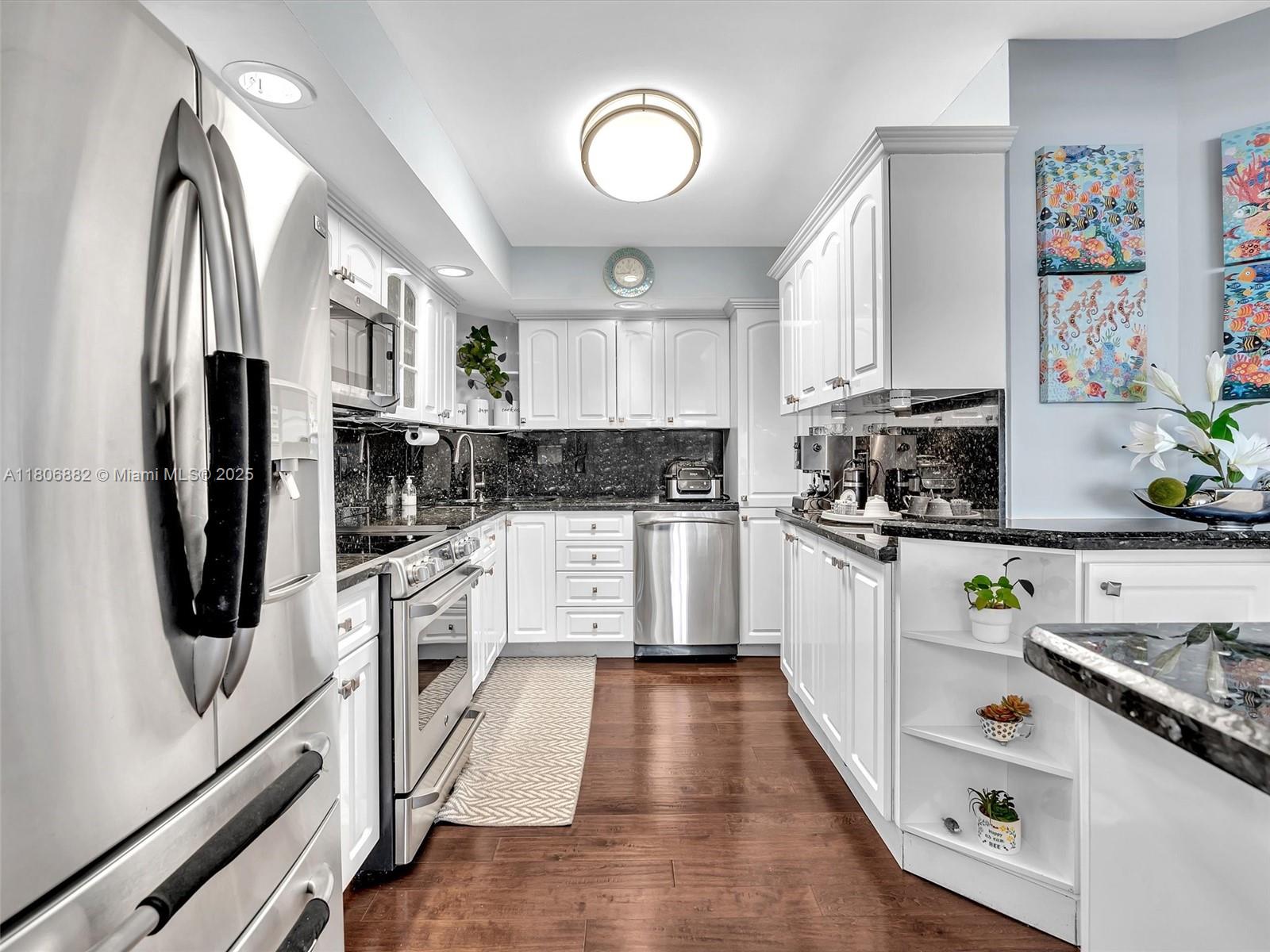 6423 Collins Avenue, Unit 409 Miami Beach, FL 33141 - Photo 13 of 66 a kitchen with white cabinets and stainless steel appliances