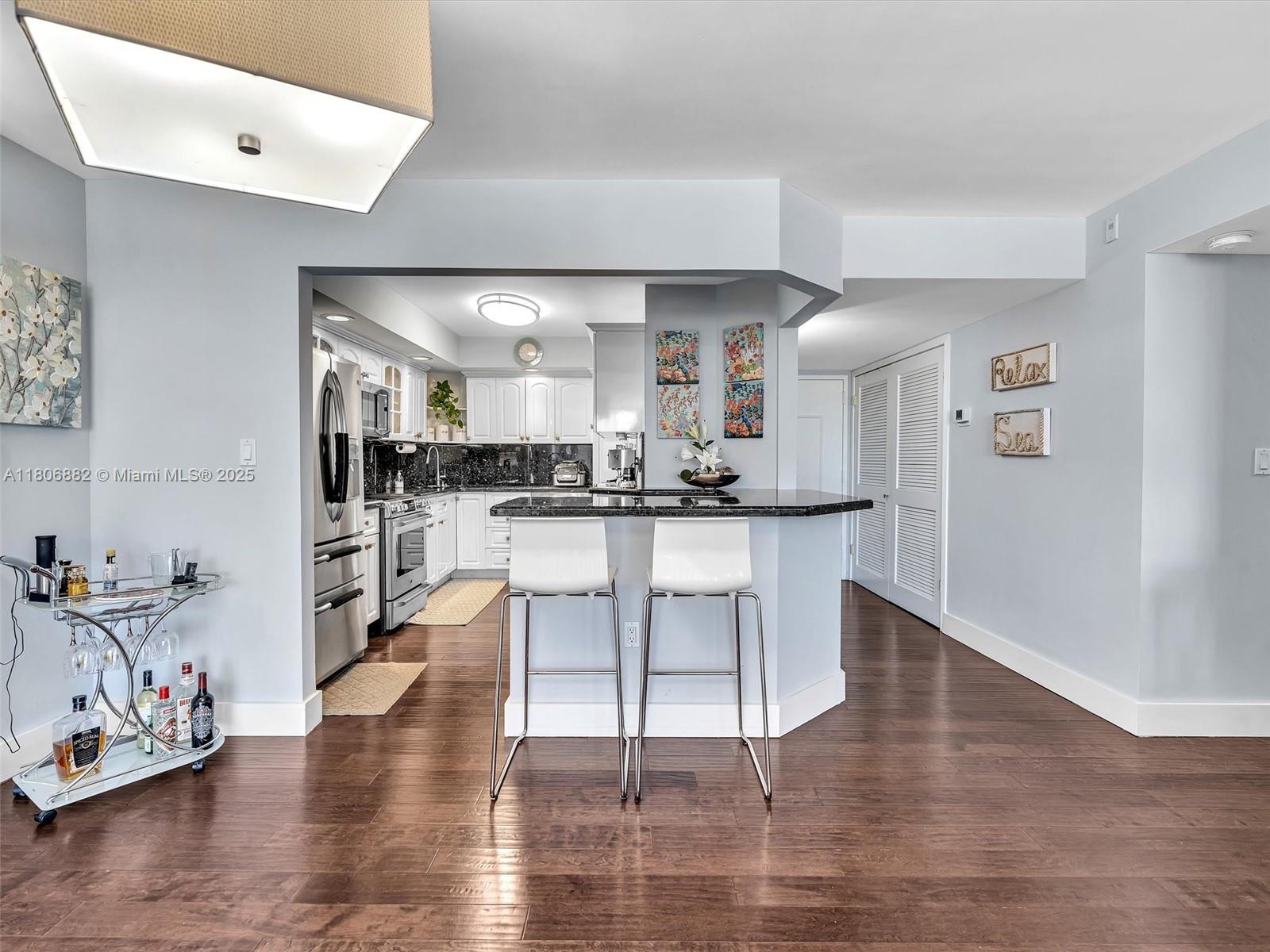 6423 Collins Avenue, Unit 409 Miami Beach, FL 33141 - Photo 17 of 66 a kitchen with stainless steel appliances kitchen island granite countertop a refrigerator a stove and white cabinets with wooden floor