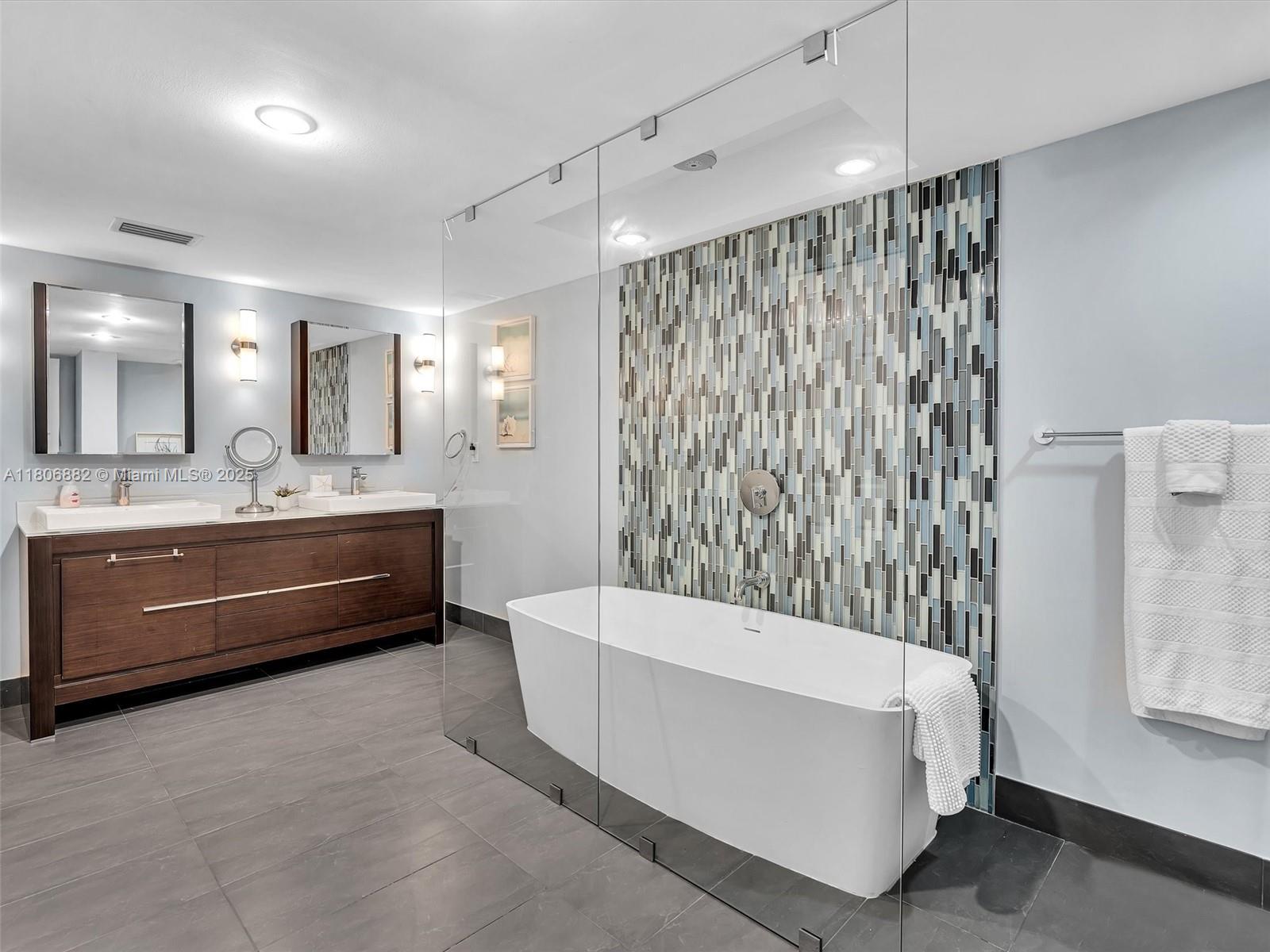 6423 Collins Avenue, Unit 409 Miami Beach, FL 33141 - Photo 41 of 66 a bathroom with a double vanity sink a mirror a bathtub and shower