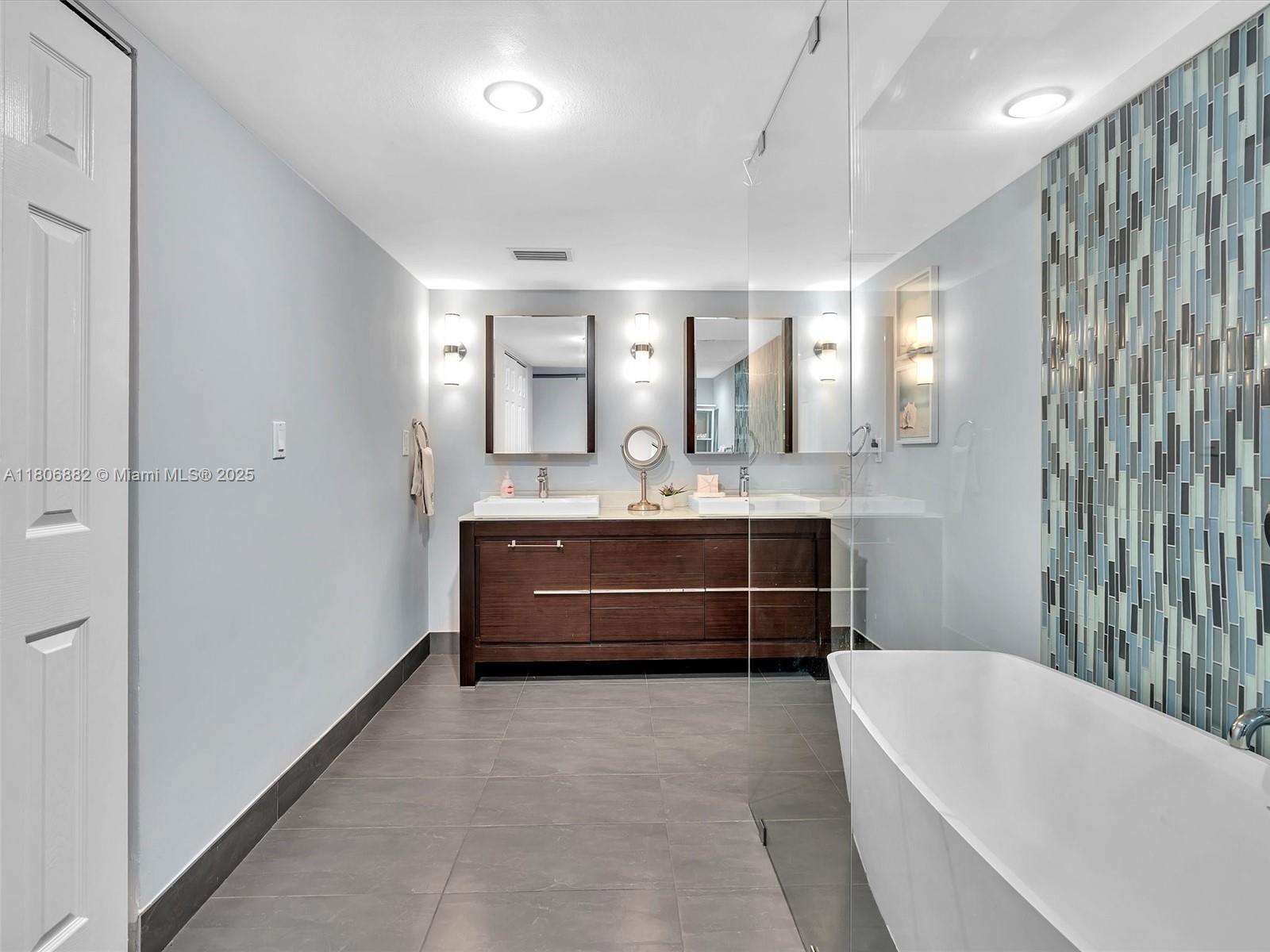 6423 Collins Avenue, Unit 409 Miami Beach, FL 33141 - Photo 44 of 66 a bathroom with a tub a double vanity sink and mirror