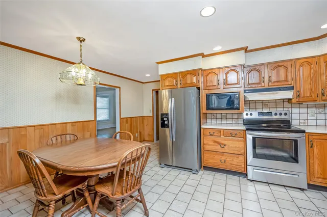 a kitchen with stainless steel appliances a stove a refrigerator island and chairs
