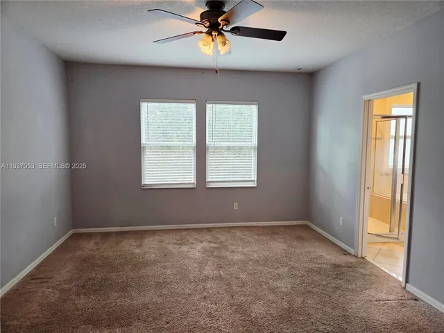 an empty room with a window and a fan