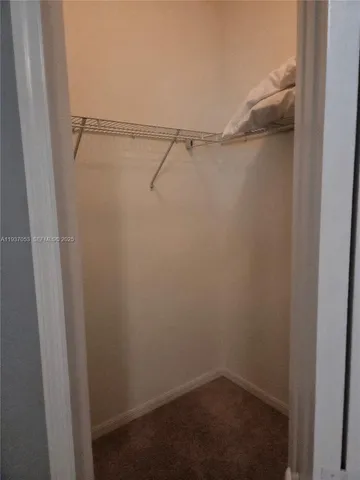 an empty room with a chandelier fan and windows