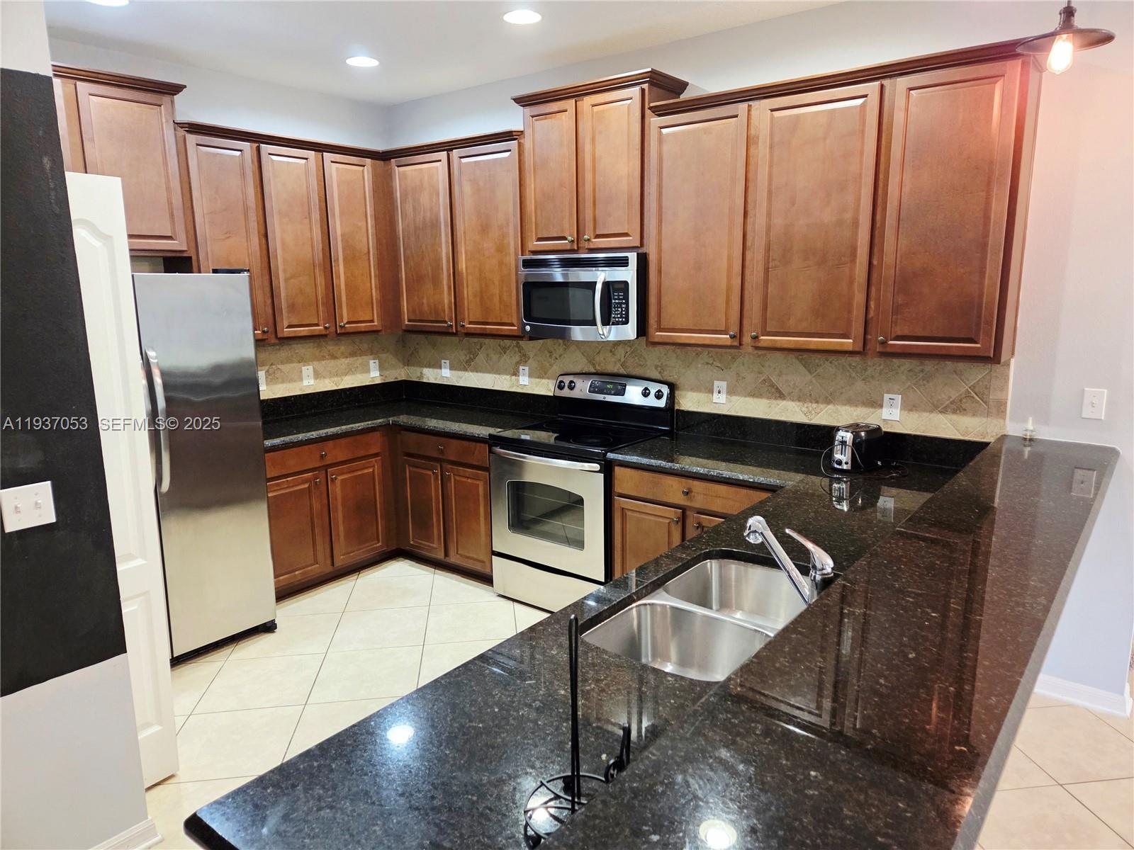 9181 Shepton Street, Unit 9181 Orlando, FL 32825 - Photo 7 of 41 a kitchen with stainless steel appliances a sink a microwave a refrigerator and cabinets