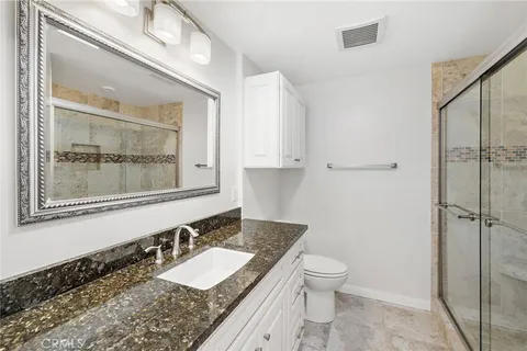 a bathroom with a granite countertop sink toilet and shower