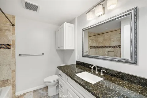 a bathroom with a granite countertop sink mirror vanity and toilet