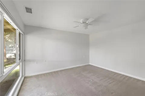 an empty room with a window and a ceiling fan