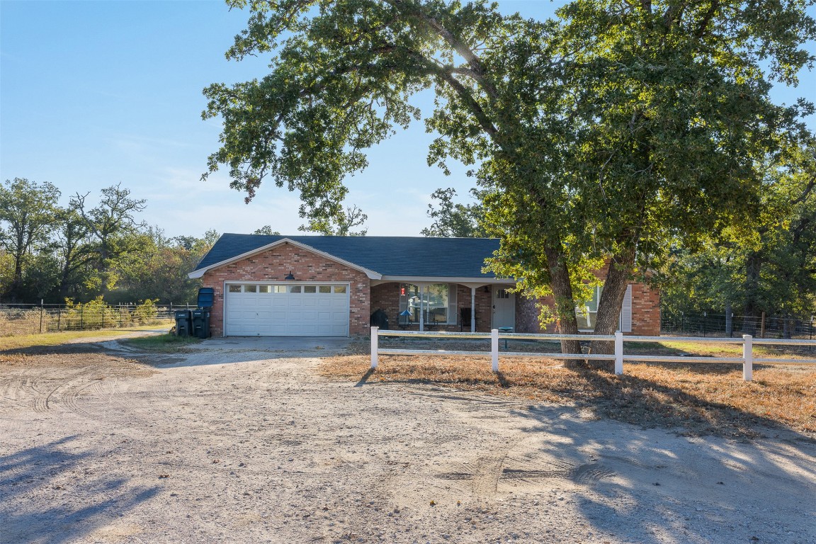 139 Farm To Market 696 Elgin, TX 78621 - Photo 26 of 27 Single story home featuring a fenced front yard, dirt driveway, an attached garage, covered porch, and brick siding