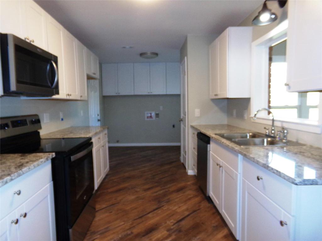 139 Farm To Market 696 Elgin, TX 78621 - Photo 9 of 27 Kitchen with appliances with stainless steel finishes, white cabinets, and dark wood-style floors