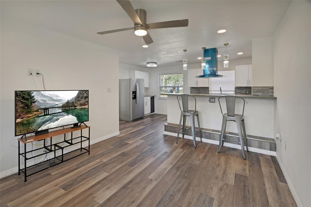 1015 East Howry Avenue Deland, FL 32724 - Photo 2 of 26 a open kitchen with stainless steel appliances granite countertop a stove top oven a refrigerator a dining table and chairs with wooden floor