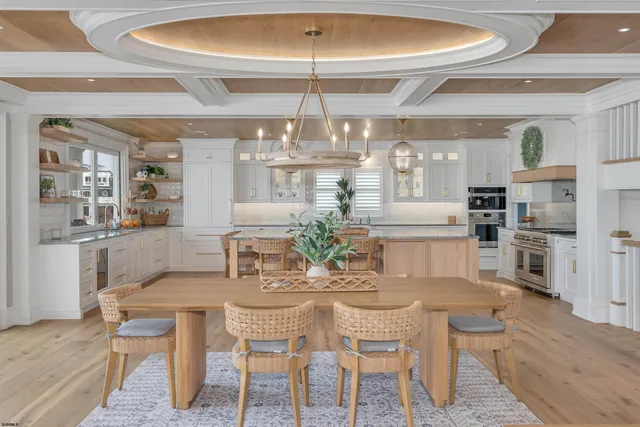 a view of a dining room with furniture a kitchen and chandelier