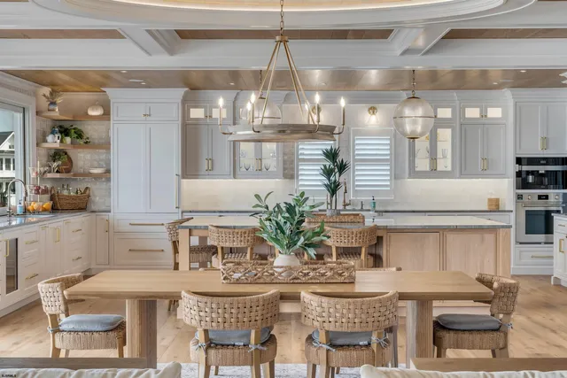 a dining hall with stainless steel appliances kitchen island granite countertop a table chairs and a oven