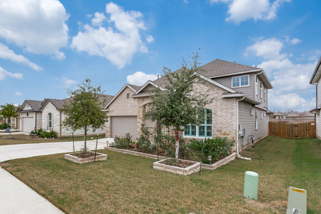 View of front of house featuring a garden, a front yard, and driveway