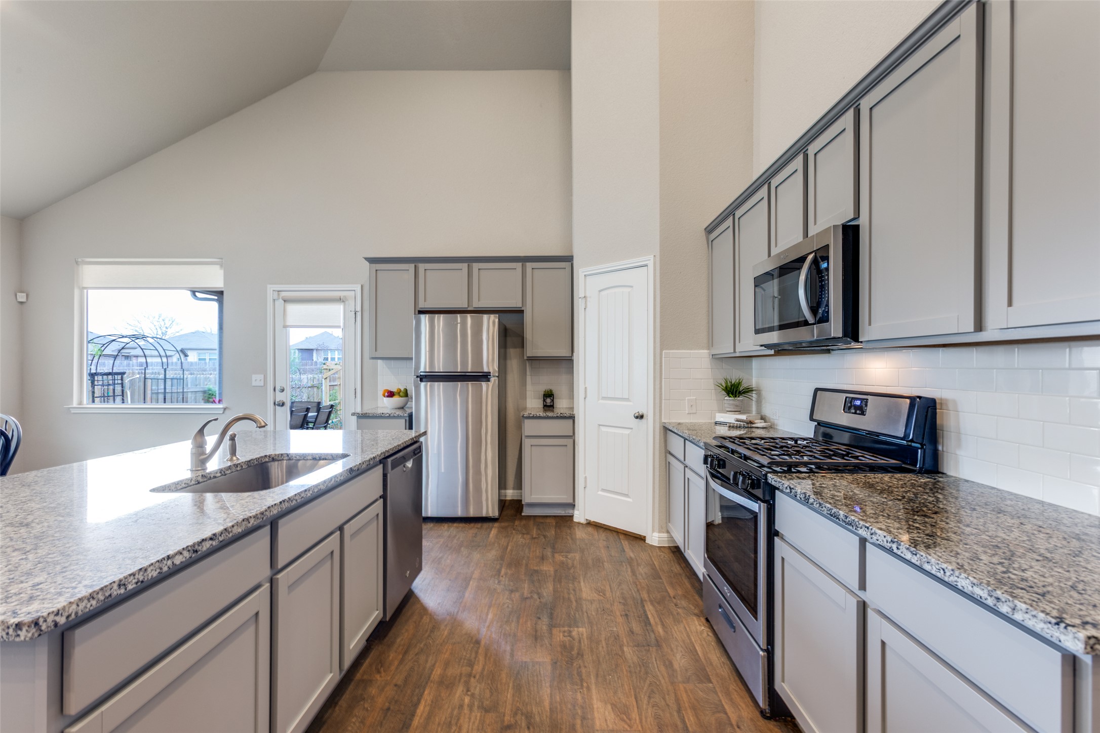 111 Rainmaker Cove Bastrop, TX 78602 - Photo 15 of 36 a kitchen with granite countertop a sink stove refrigerator and cabinets