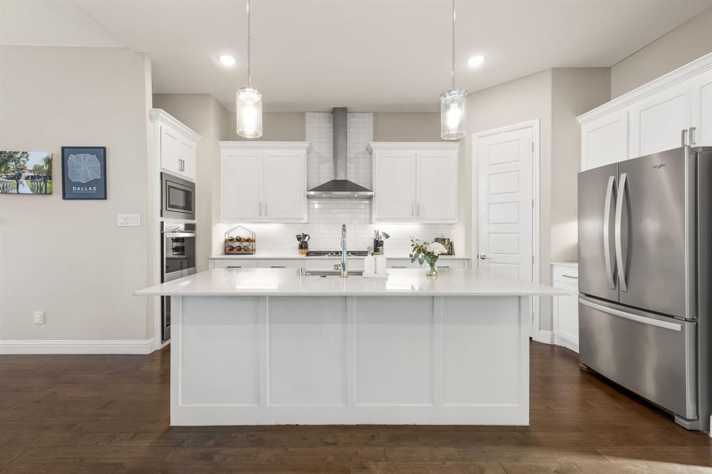 2270 English Ivy Road Frisco, TX 75033 - Photo 11 of 39 a kitchen with stainless steel appliances granite countertop a refrigerator a stove a sink and white cabinets with wooden floor