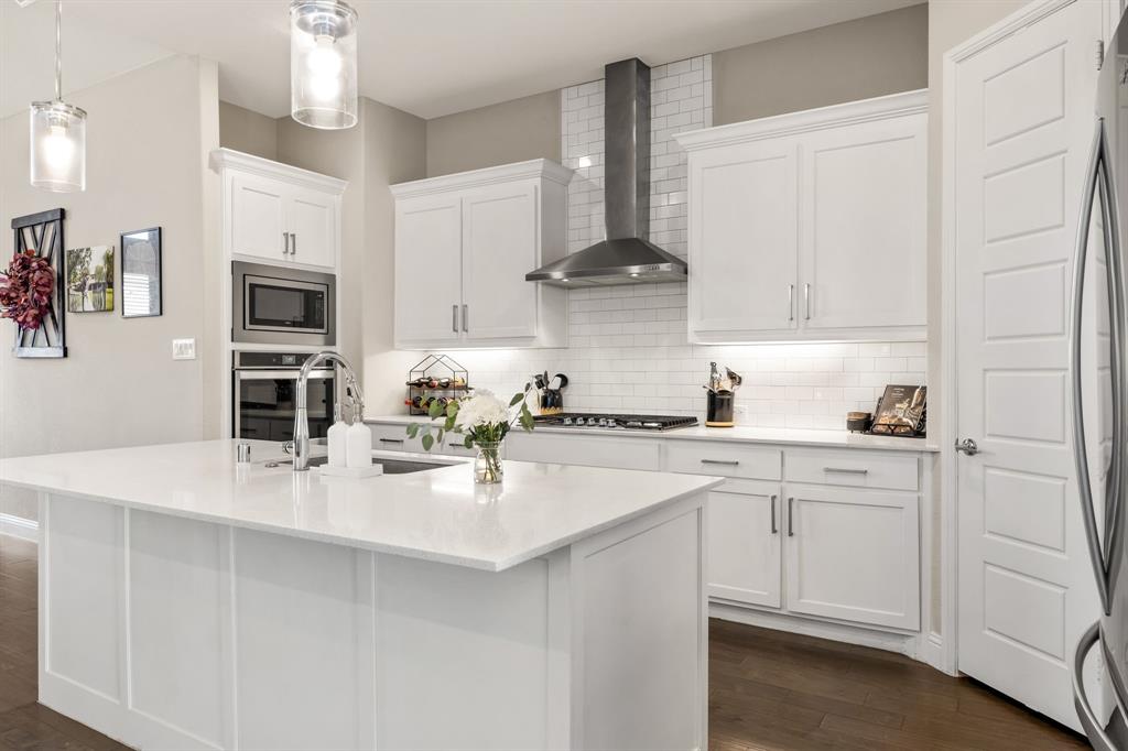 2270 English Ivy Road Frisco, TX 75033 - Photo 8 of 39 a kitchen with white cabinets and stainless steel appliances