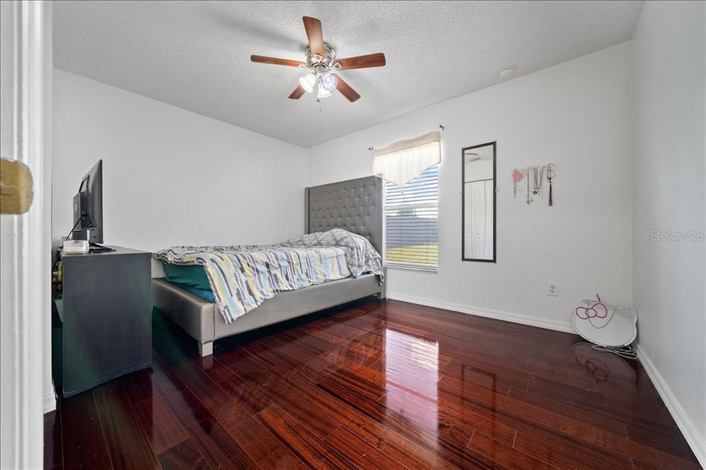 4721 Southwest 142nd Place Road Ocala, FL 34473 - Photo 18 of 25 a bedroom with a bed ceiling fan and a wooden floor