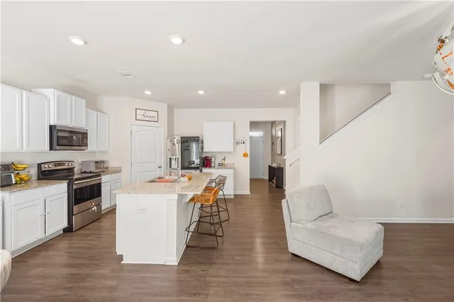 a living room with stainless steel appliances kitchen island granite countertop a couch and a view of kitchen