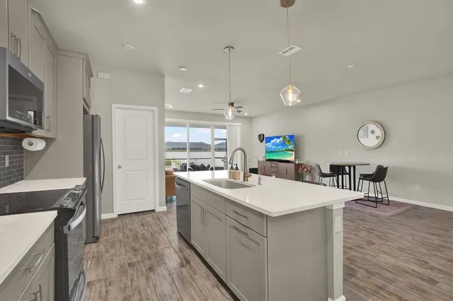 a large kitchen with a sink a counter space and stainless steel appliances