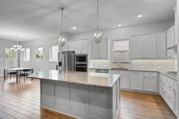 a large kitchen with granite countertop a large island in the center and stainless steel appliances