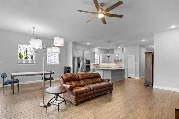 a living room with stainless steel appliances kitchen island furniture and a wooden floor
