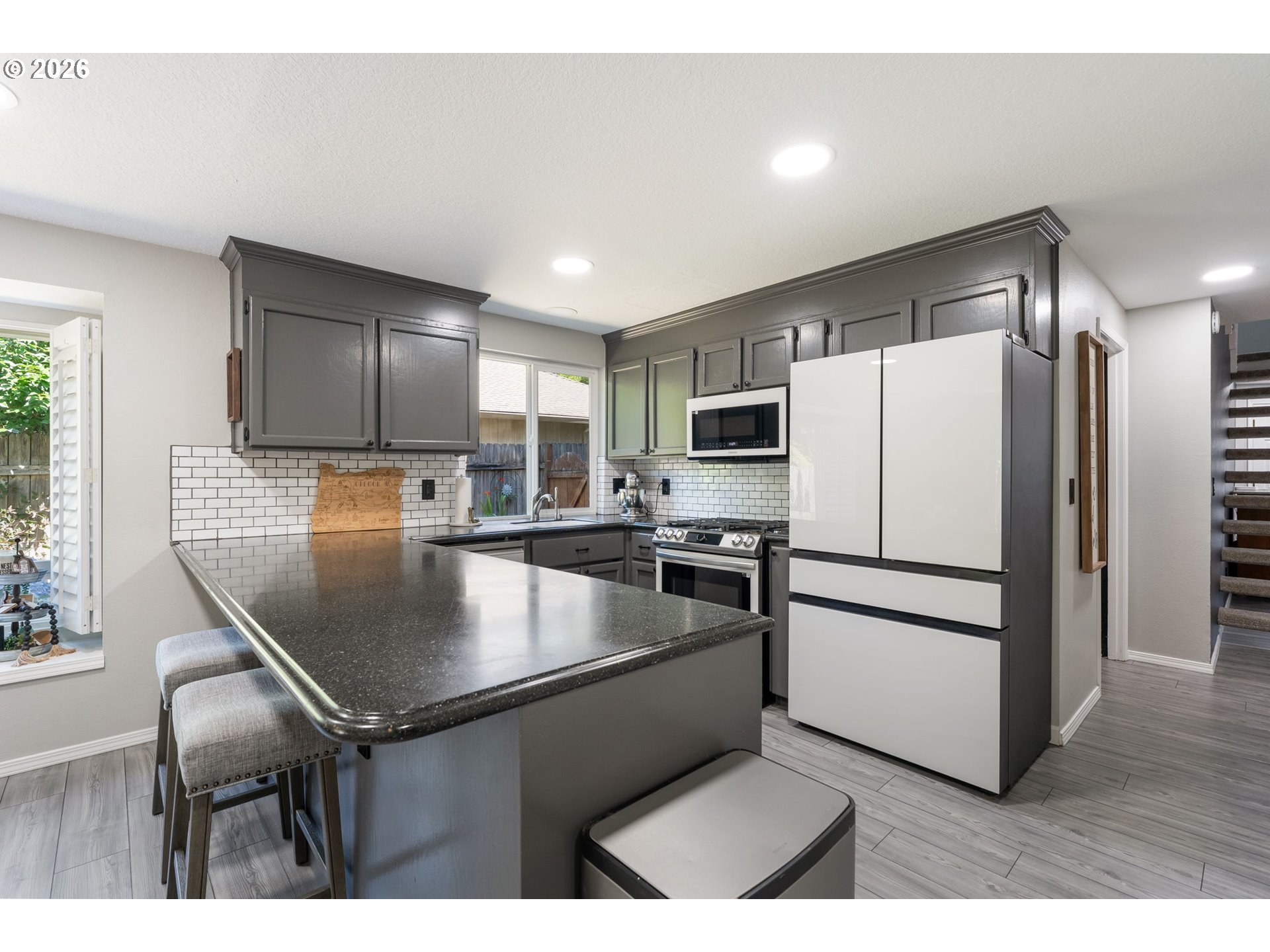 14877 Southwest Oregon Trail Lane Beaverton, OR 97006 - Photo 7 of 41 a kitchen with stainless steel appliances granite countertop a refrigerator a stove a microwave oven a sink with island and chairs