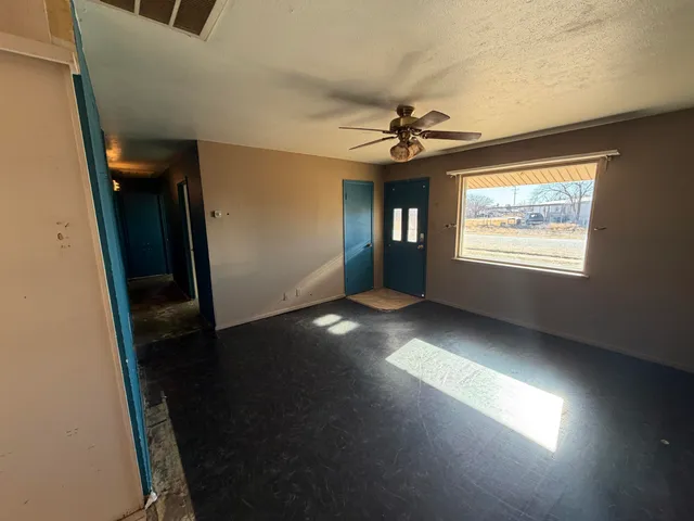 an empty room with windows and fan