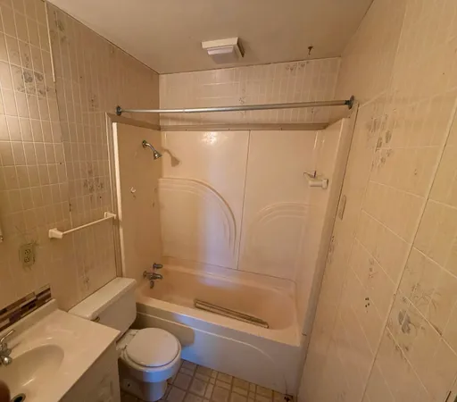 a bathroom with a granite countertop bathtub shower sink vanity and toilet