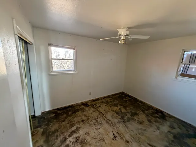 an empty room with windows and ceiling fan
