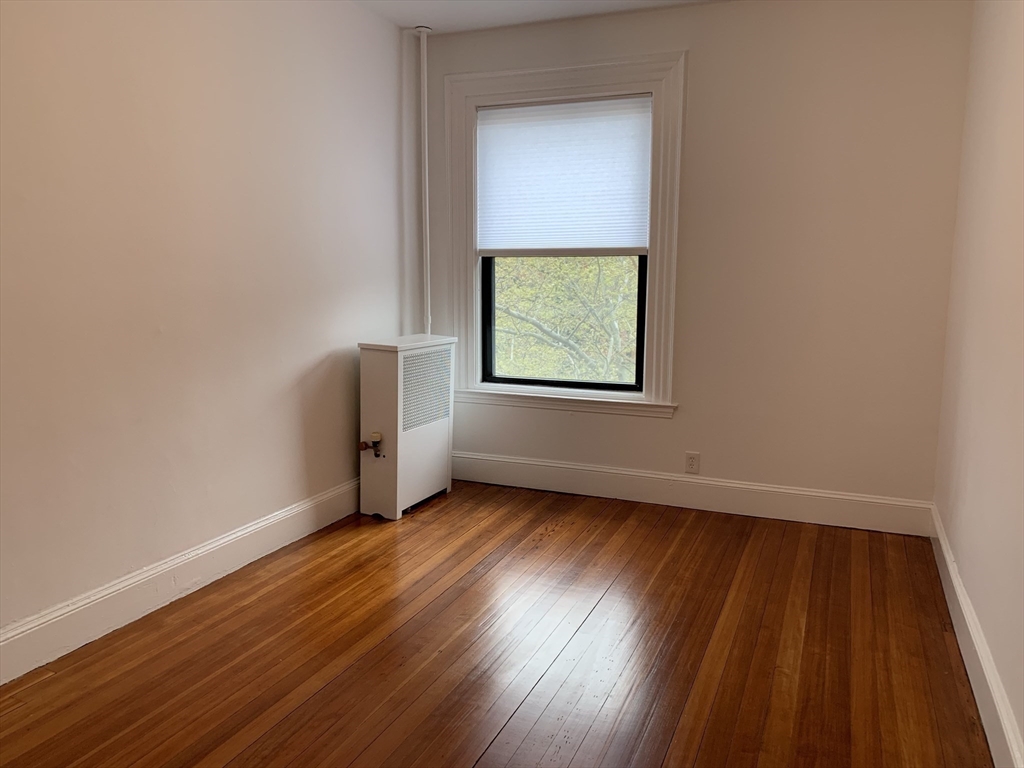 1064 Beacon Street, Unit 9 Brookline, MA 02446 - Photo 9 of 19 an empty room with wooden floor and windows