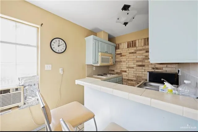 a living room with stainless steel appliances furniture a fireplace and a open kitchen