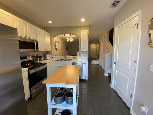 a kitchen with stainless steel appliances kitchen island granite countertop a refrigerator and a stove top oven