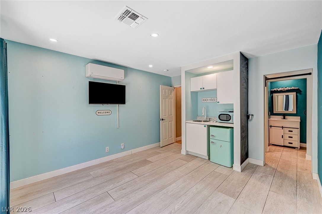 4153 Woodcrest Road Las Vegas, NV 89121 - Photo 34 of 58 A well-lit studio space with light plank flooring and a compact kitchen area.