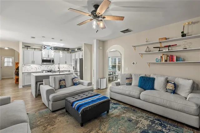a living room with furniture kitchen view and a chandelier