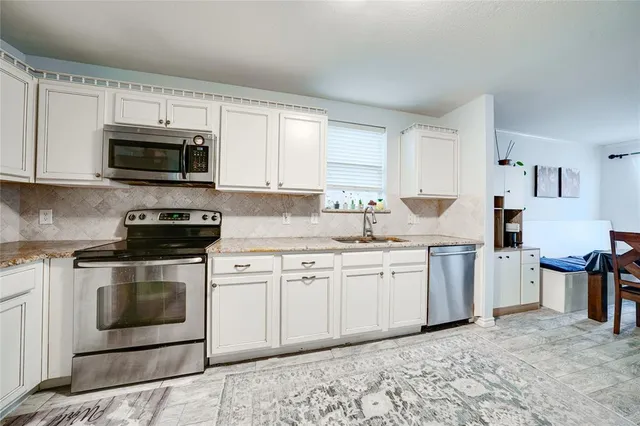 a kitchen with granite countertop a sink a stove and cabinets