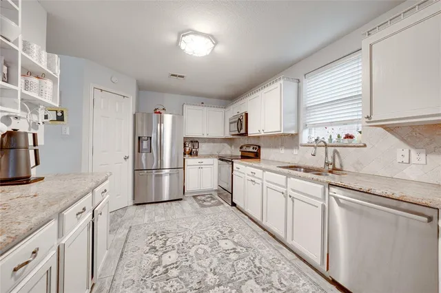 a kitchen with granite countertop a sink stainless steel appliances and cabinets