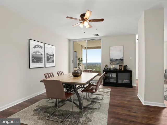 a view of an empty room with wooden floor and a kitchen