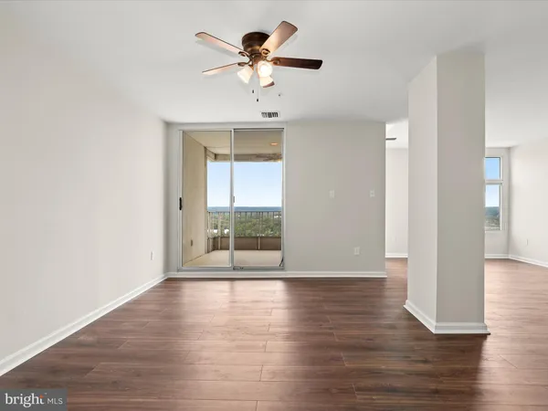 a view of an empty room with wooden floor and a window