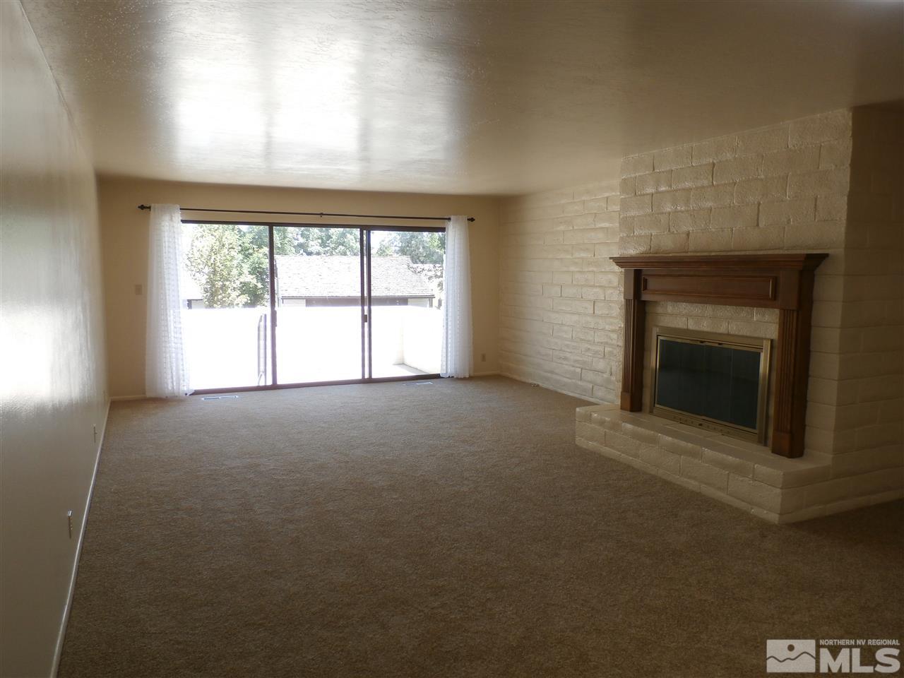 5062 Lakeridge Terrace East Reno, NV 89509 - Photo 7 of 13 an empty room with a fireplace and windows