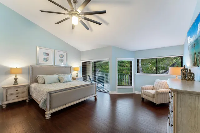 a bedroom with a bed couch and a large window with wooden floor