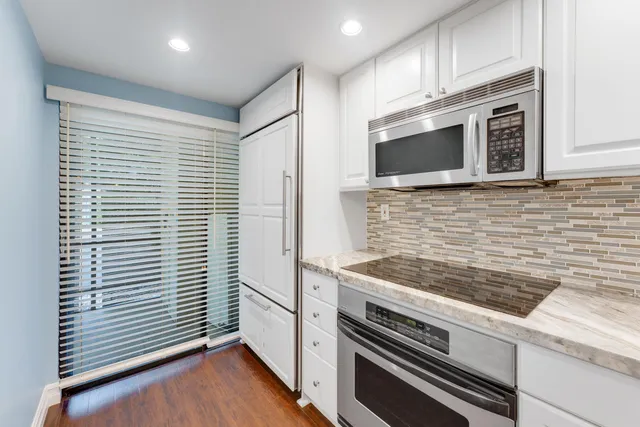 a kitchen with granite countertop cabinets stainless steel appliances and wooden floor