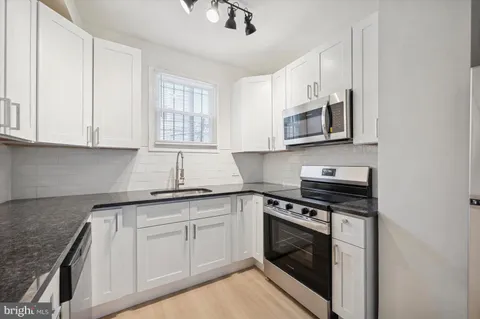 a kitchen with granite countertop white cabinets stainless steel appliances and a sink