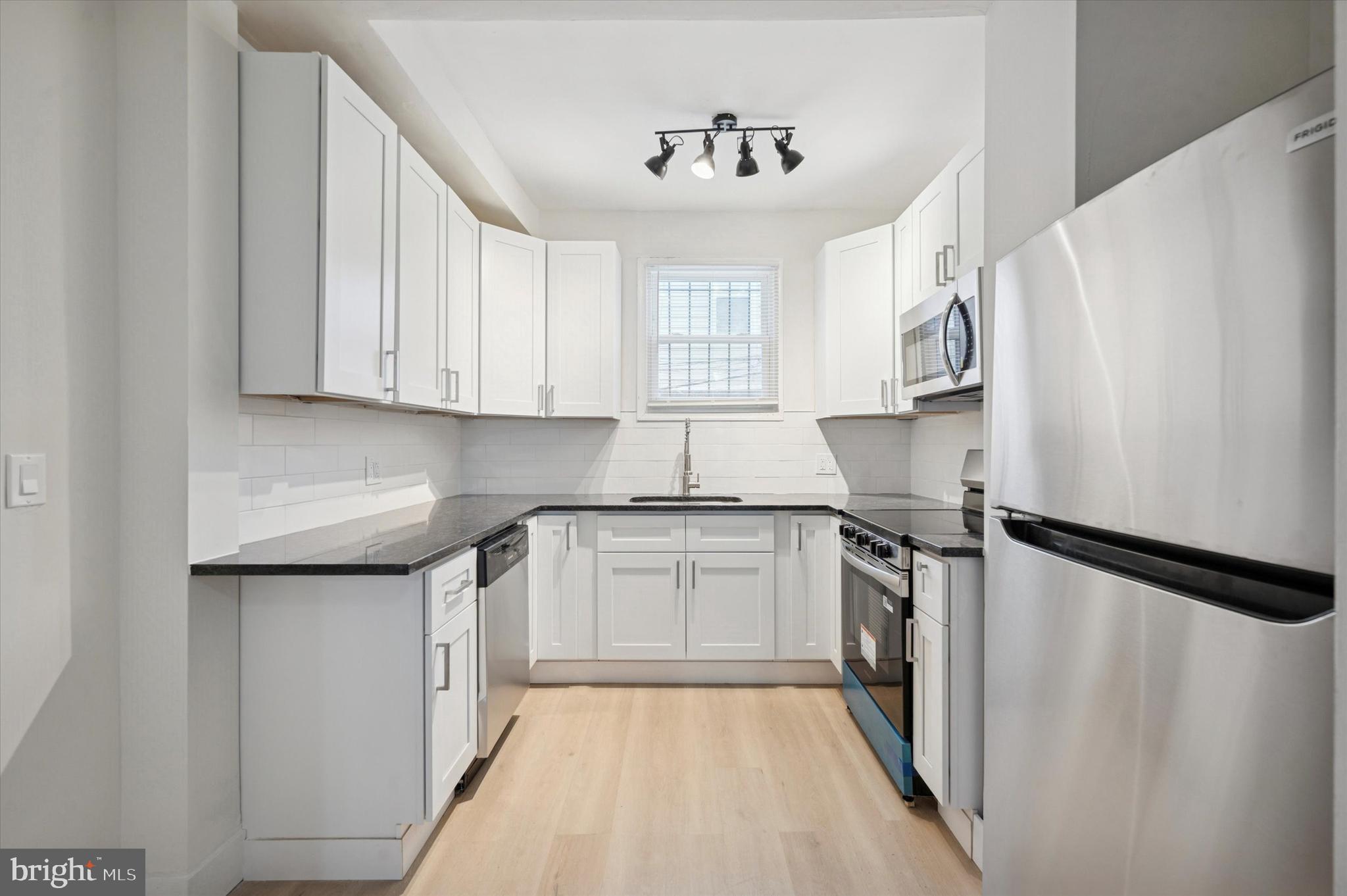 2457 North Patton Street Philadelphia, PA 19132 - Photo 9 of 23 a kitchen with granite countertop white cabinets and white appliances