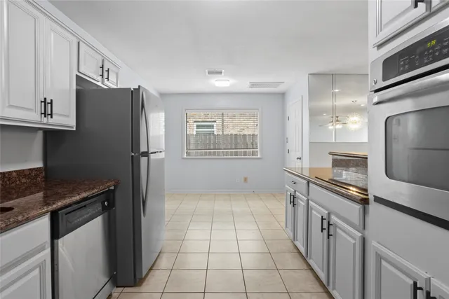 a kitchen with granite countertop a refrigerator and a stove top oven