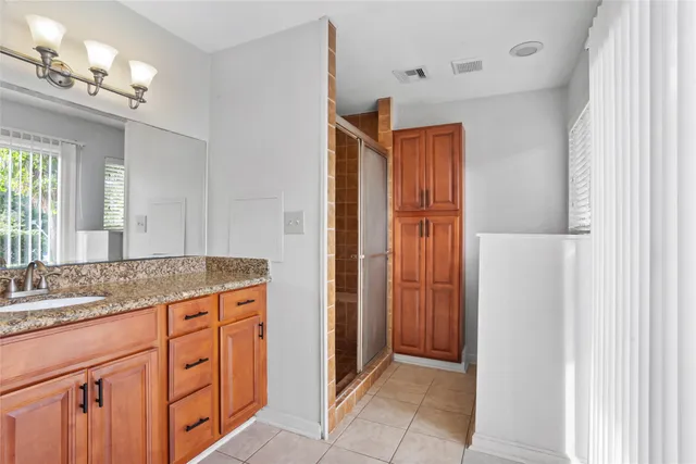 a bathroom with a granite countertop sink a mirror a vanity and a shower