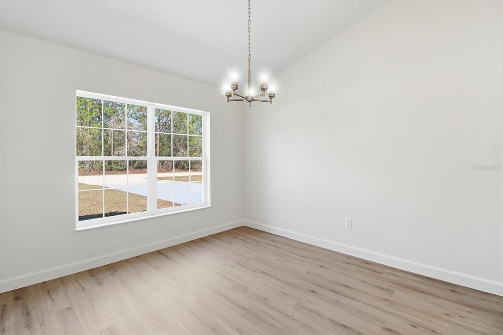 13418 Cormorant Road Weeki Wachee, FL 34614 - Photo 11 of 46 an empty room with wooden floor chandelier and windows