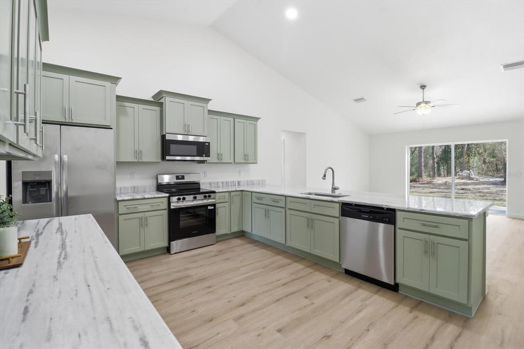 13418 Cormorant Road Weeki Wachee, FL 34614 - Photo 14 of 46 a large kitchen with cabinets wooden floor and stainless steel appliances