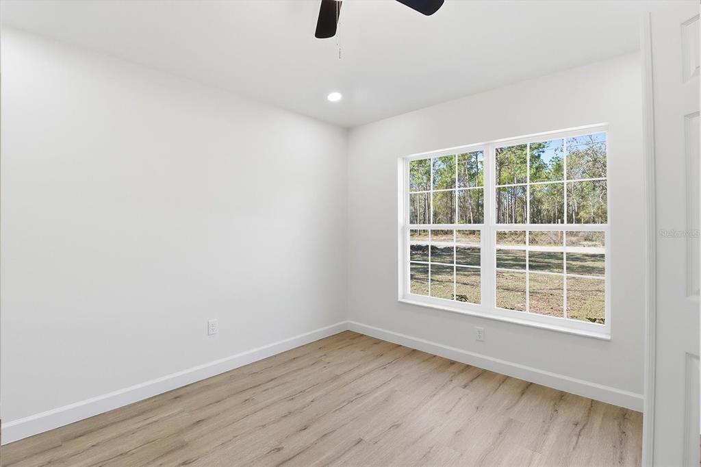 13418 Cormorant Road Weeki Wachee, FL 34614 - Photo 9 of 46 a view of an empty room with a window and wooden floor