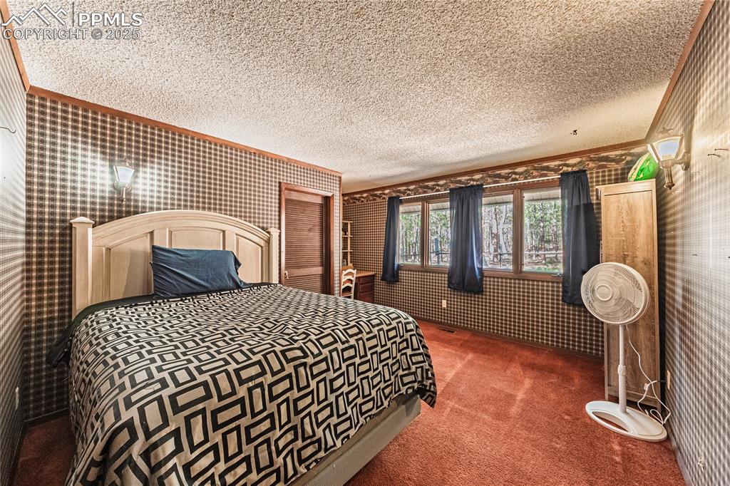 7190 Burgess Road Colorado Springs, CO 80908 - Photo 45 of 50 a bedroom with a bed and dresser with wooden floor